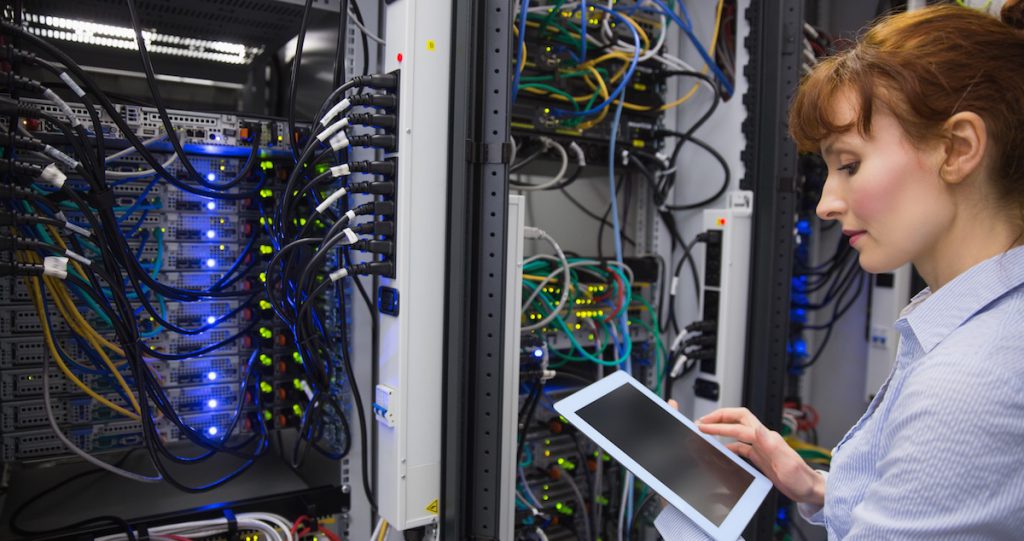 Technician using tablet pc while analysing server