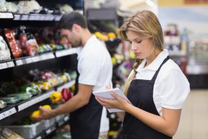 Serious-staff-woman-wrting-on-notepad-at-supermarket