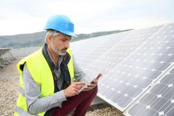 Mature-field engineer-on-building-roof-checking-solar-panels